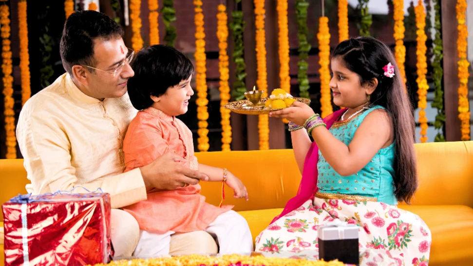 Raksha Bandhan celebration with a sister tying a rakhi on her brother’s wrist and exchanging festive sweets