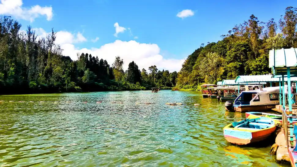 Scenic Ooty Lake with boating activities surrounded by lush greenery and misty hills